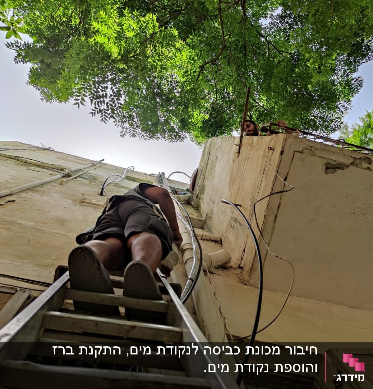 אדם על סולם ליד צינורות על קיר חיצוני